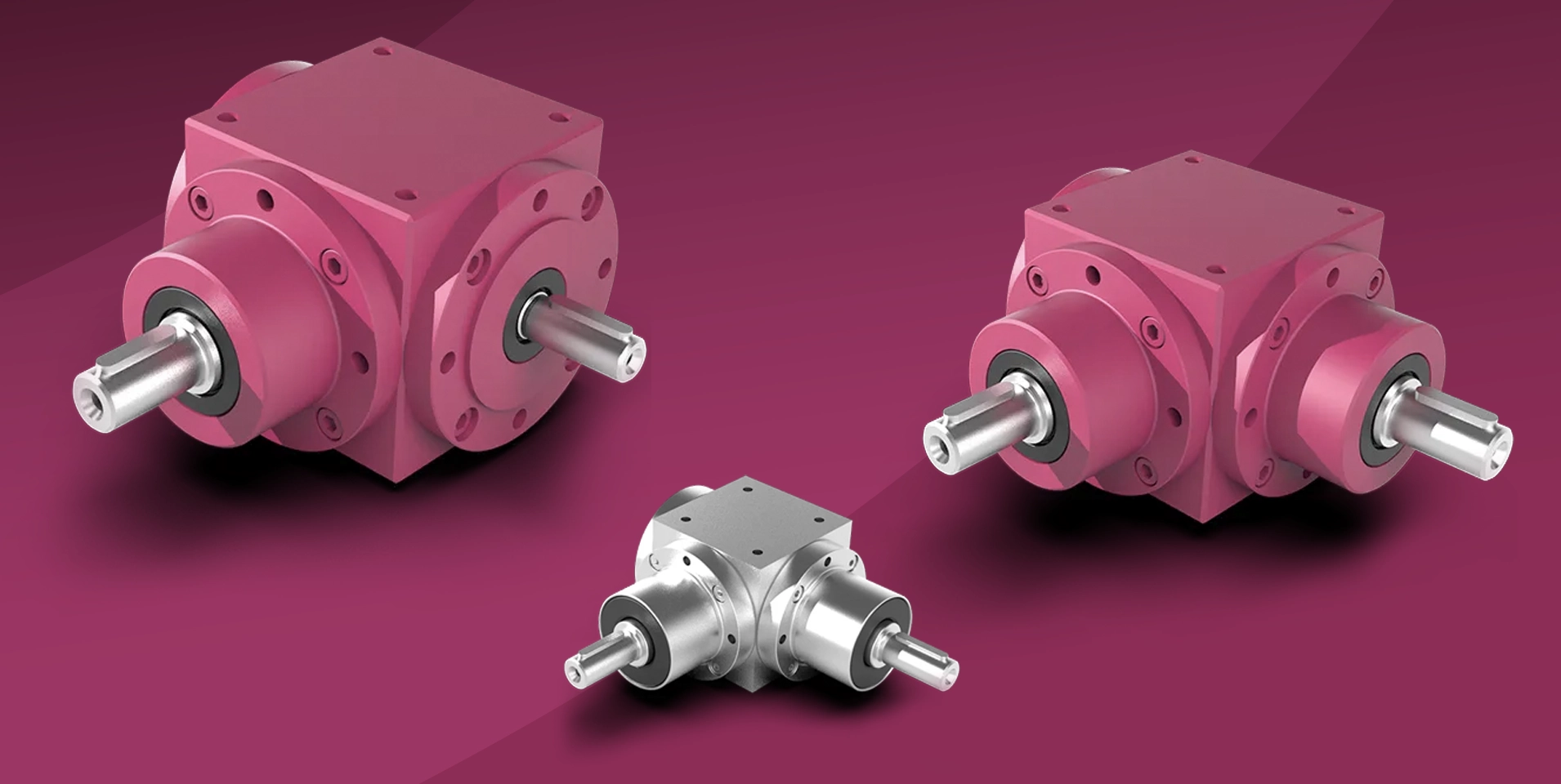 Drei Kegelradgetriebe von ATEK Drive Solutions in unterschiedlichen Baugrößen, zwei in Magenta lackiert und eines in Edelstahlausführung